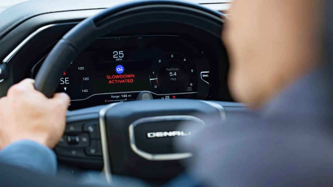 An over the shoulder view of a vehicle's steering wheel and dashboard