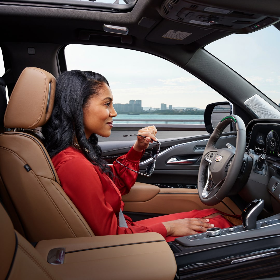 woman holding glasses Smiling While in her Vehicle Using OnStar Super Cruise