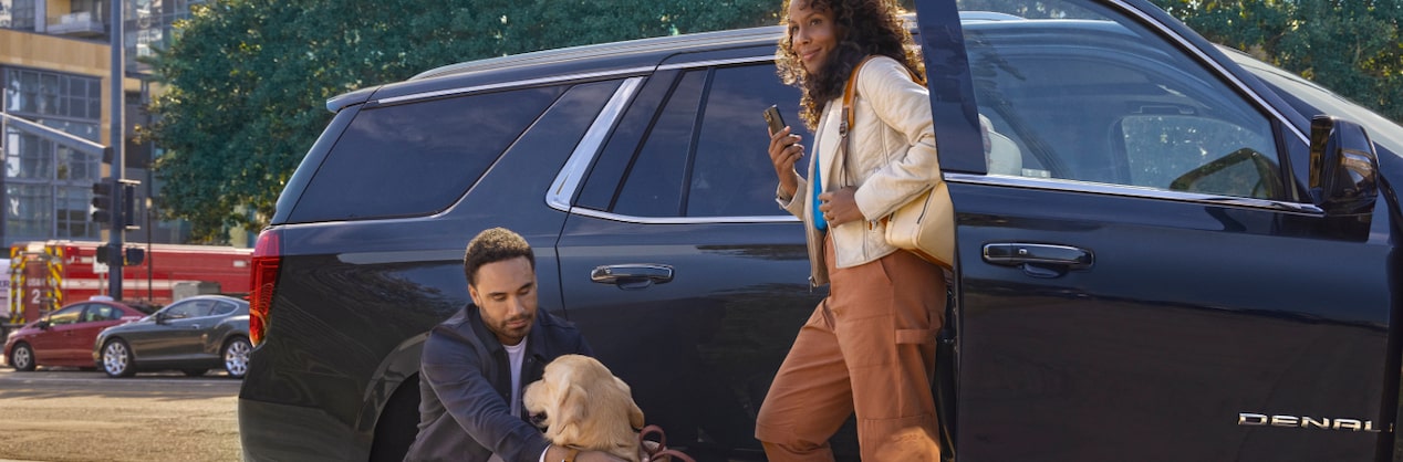 Man and Woman Standing Next To GMC Vehicle with Their Dog