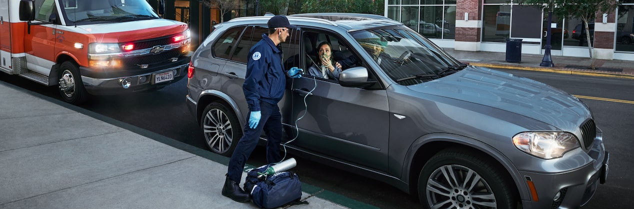 EMT Standing at Passenger Side Window Giving Woman Oxygen with Air Mask