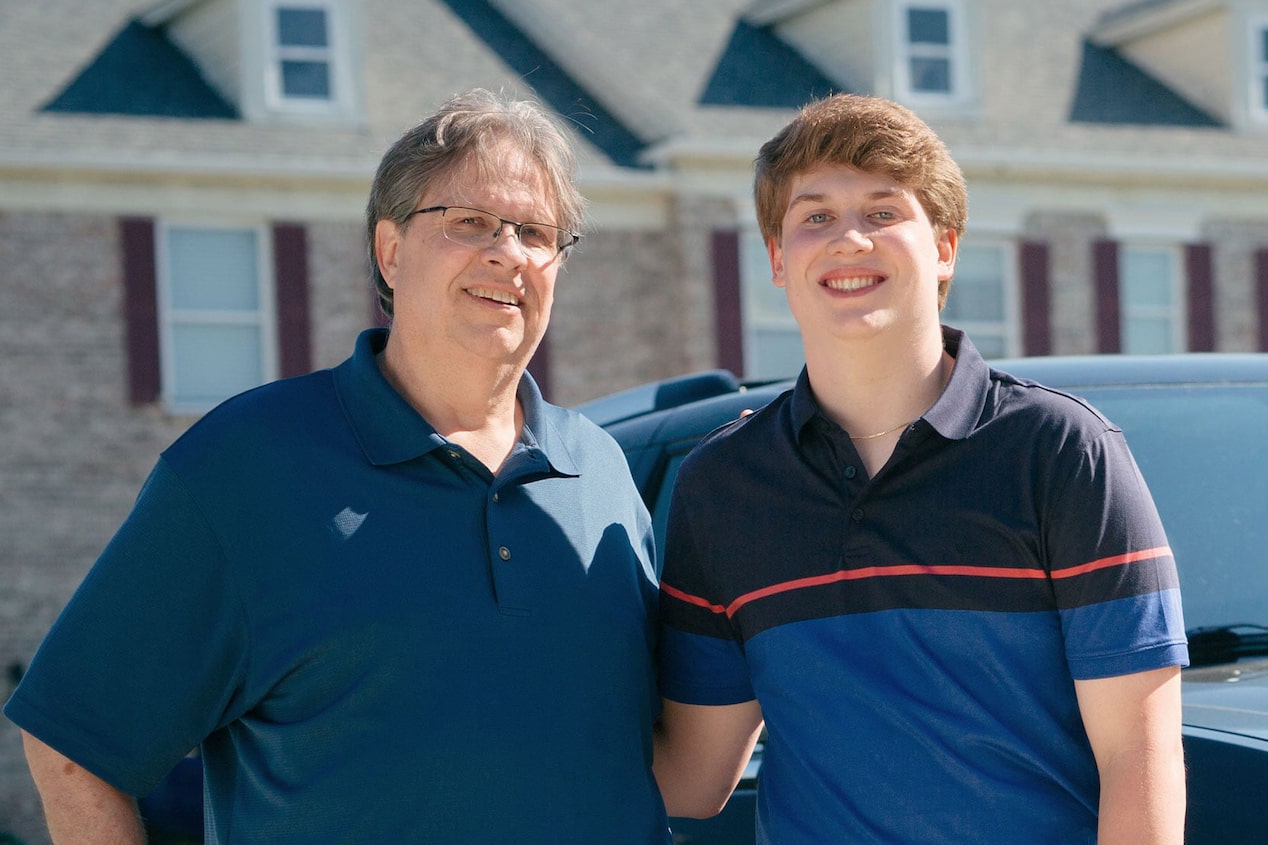 Father and Son Standing Side by Side in Driveway Smiling