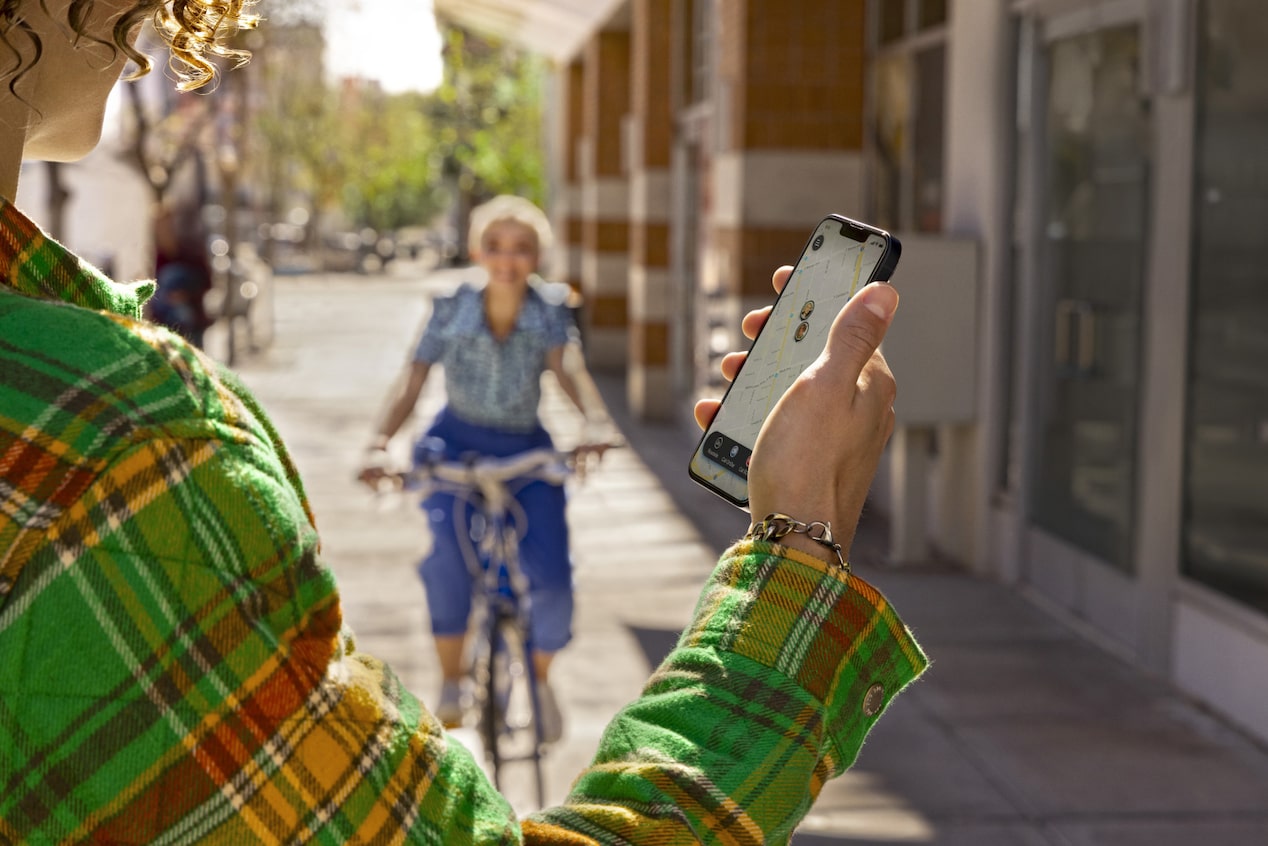 User Checks Guardian App While Friend Approaches on a Bike