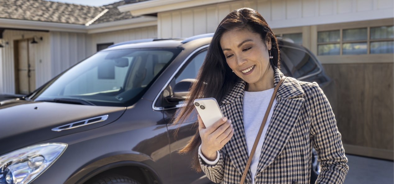 Women Looking at Her Phone Standing Next to Her GM Vehicle