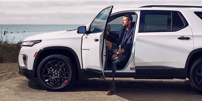 A man with a prosthetic leg stepping out of his GM vehicle at the beach