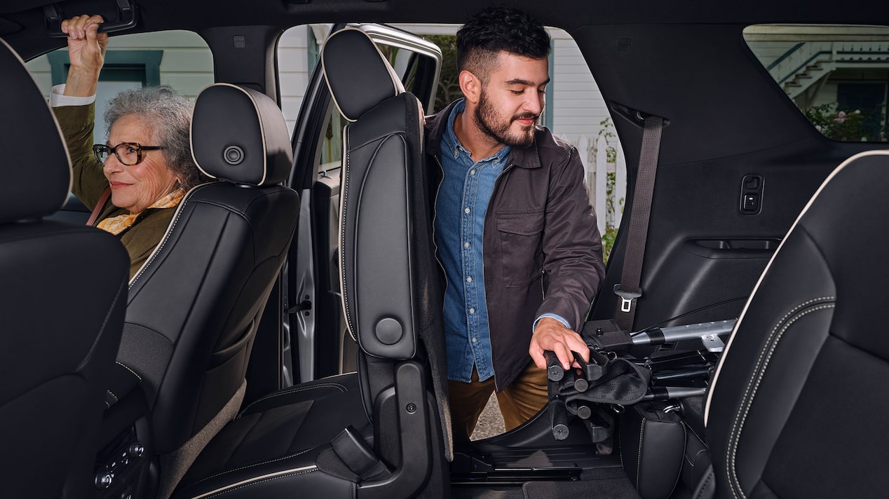 A man using General Motors adjustable seats to load a walker into a vehicle