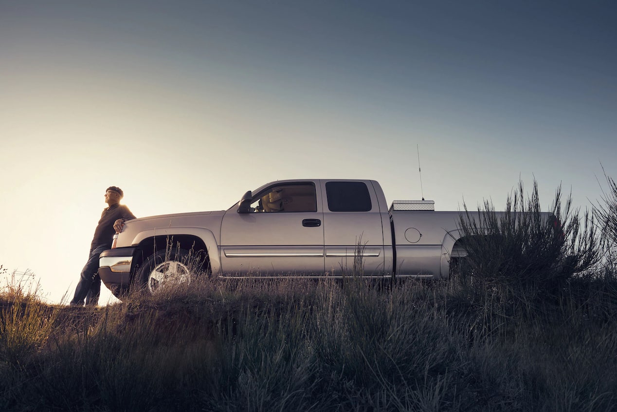 Man Leaning on Front of GM Truck in the Sunset