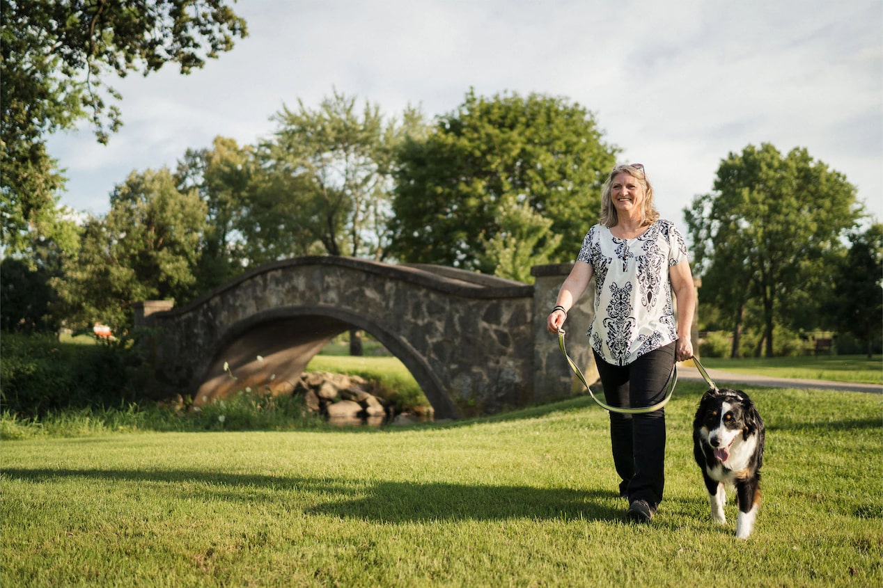 Woman Walking Her Dog Near a Small Bridge