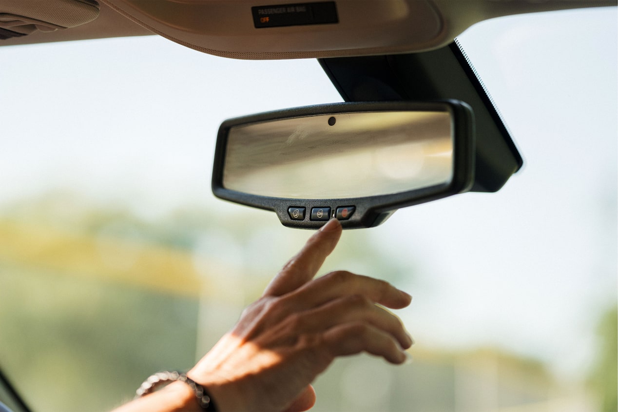 Hand Pressing OnStar Button on a Rear View Mirror 