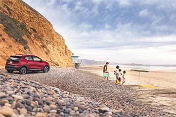 A family arriving at the beach with their GM vehicle parked in the background