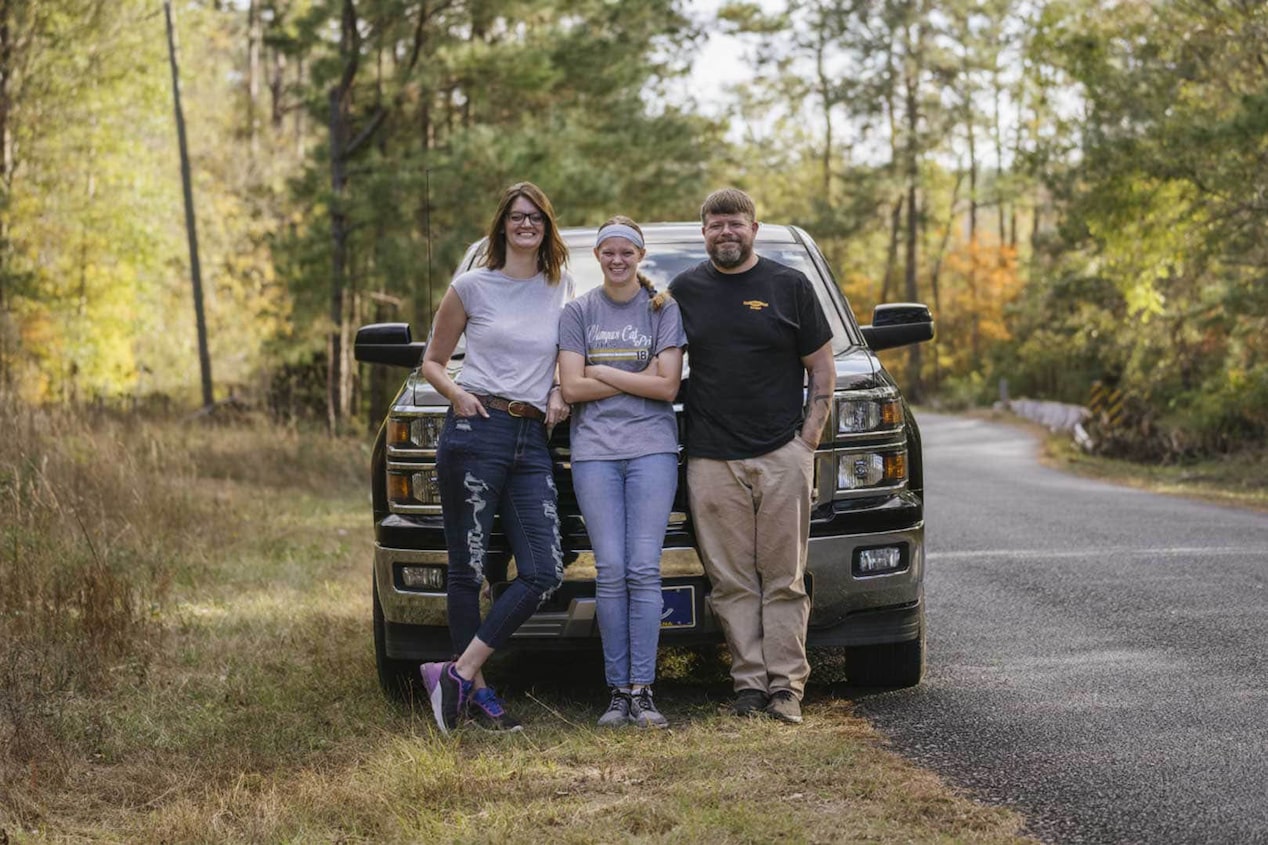 Family of Three Leaning Against Chevy Pickup Truck Smiling  