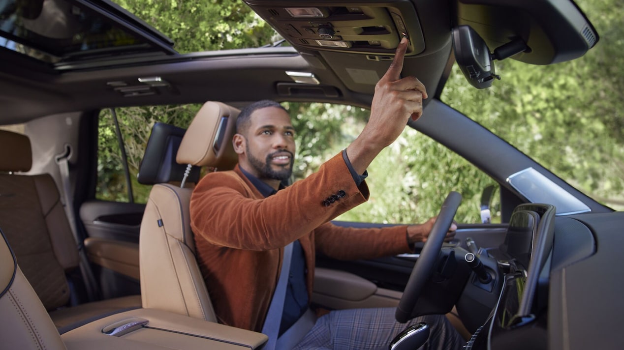 Male Driver Wearing Brown Jacket Pressing the OnStar Button 