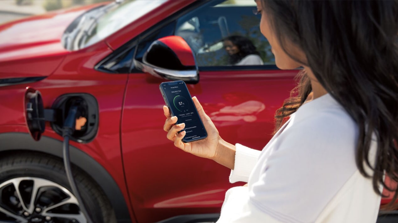 A Woman Monitors Her Vehicle's Charge with her Mobile Device 