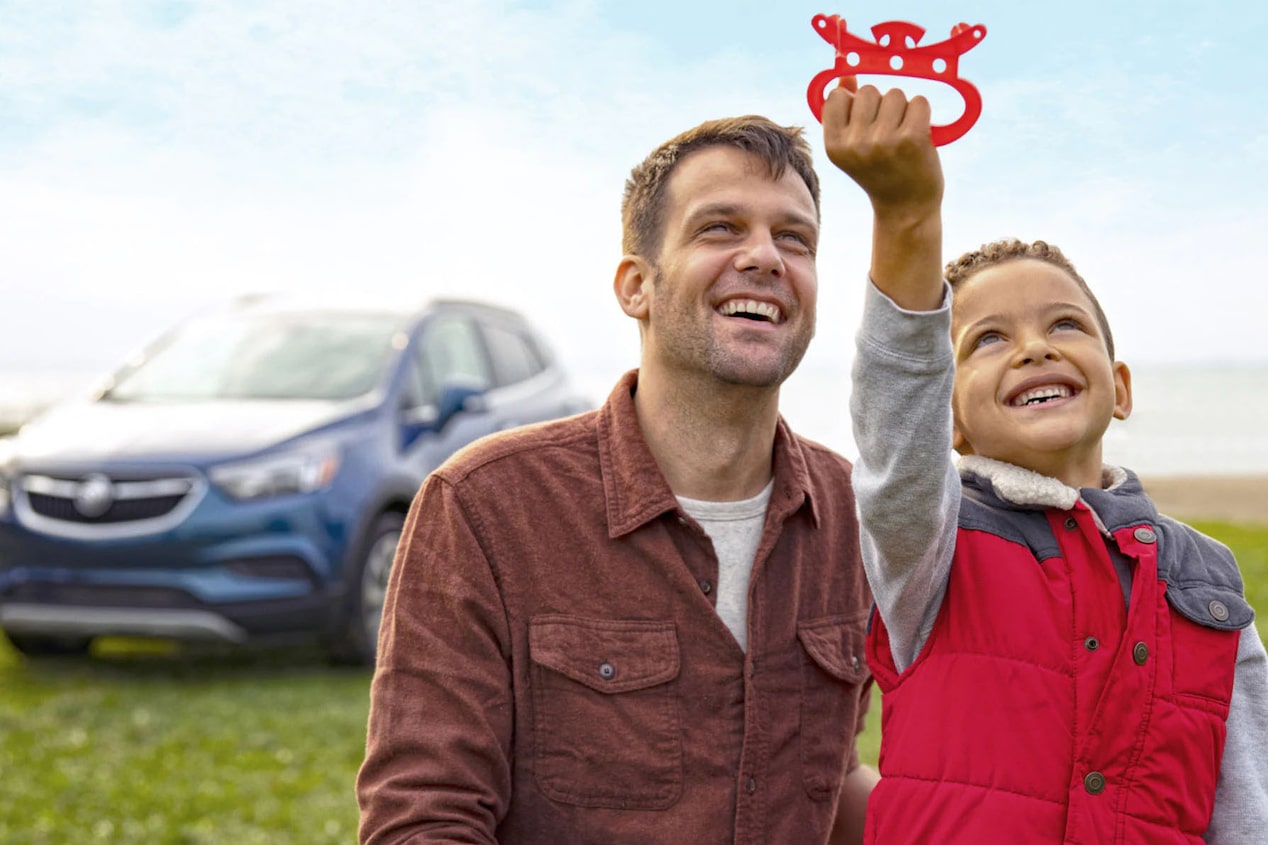 Dad and Son Play With a Kite in front of Their Buick