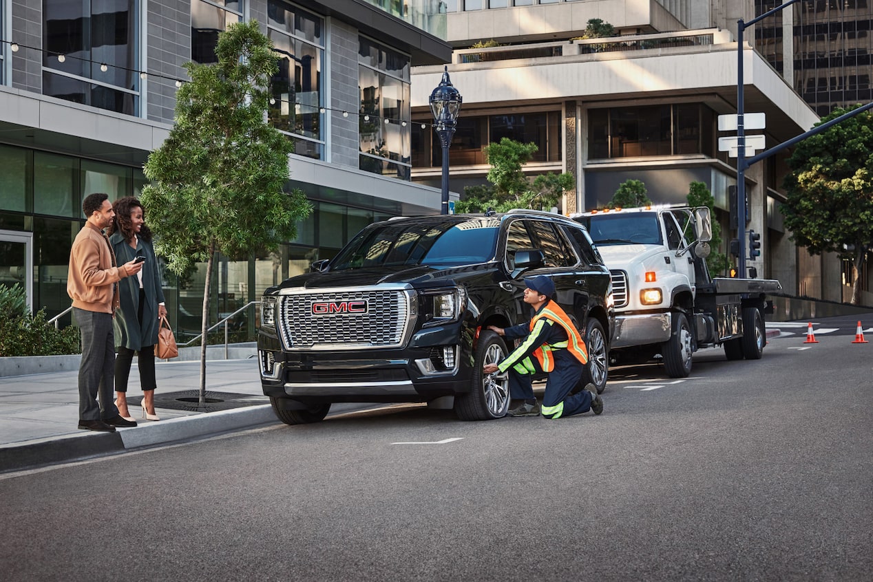 Roadside Assistance Works on a GMC SUV in Front of an Office Building