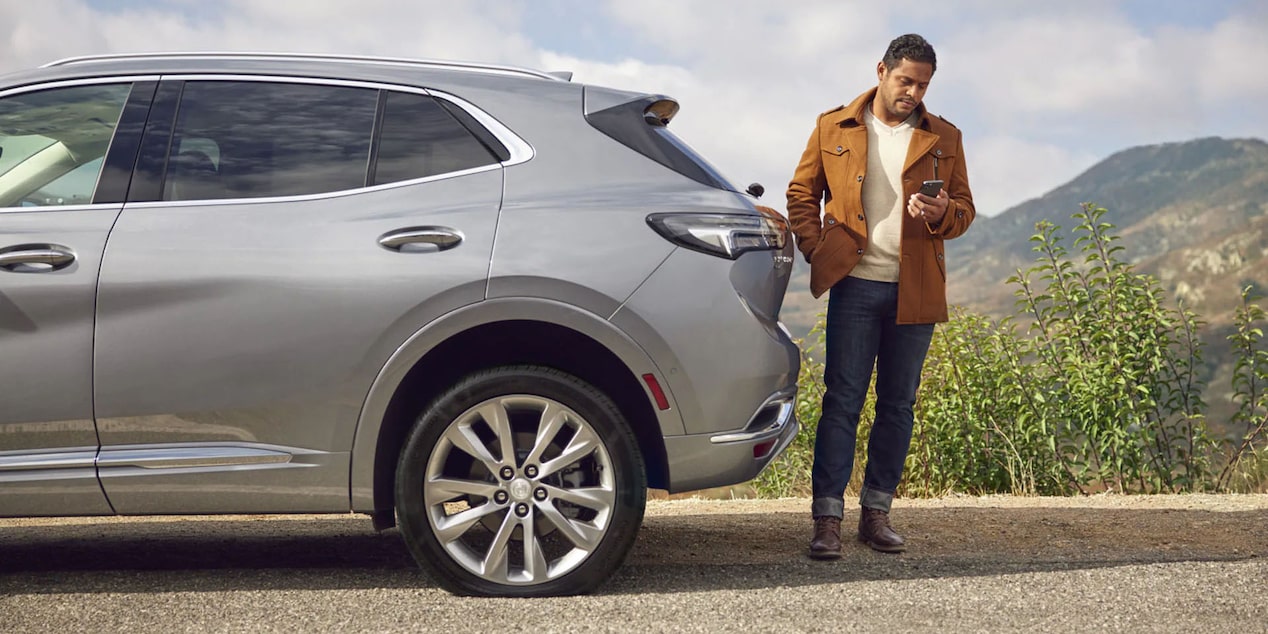 Man Stands Behind his GM SUV While Checking his Phone