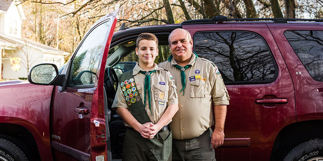 Scoutmaster and boy Scout Standing Next to Their Vehicle